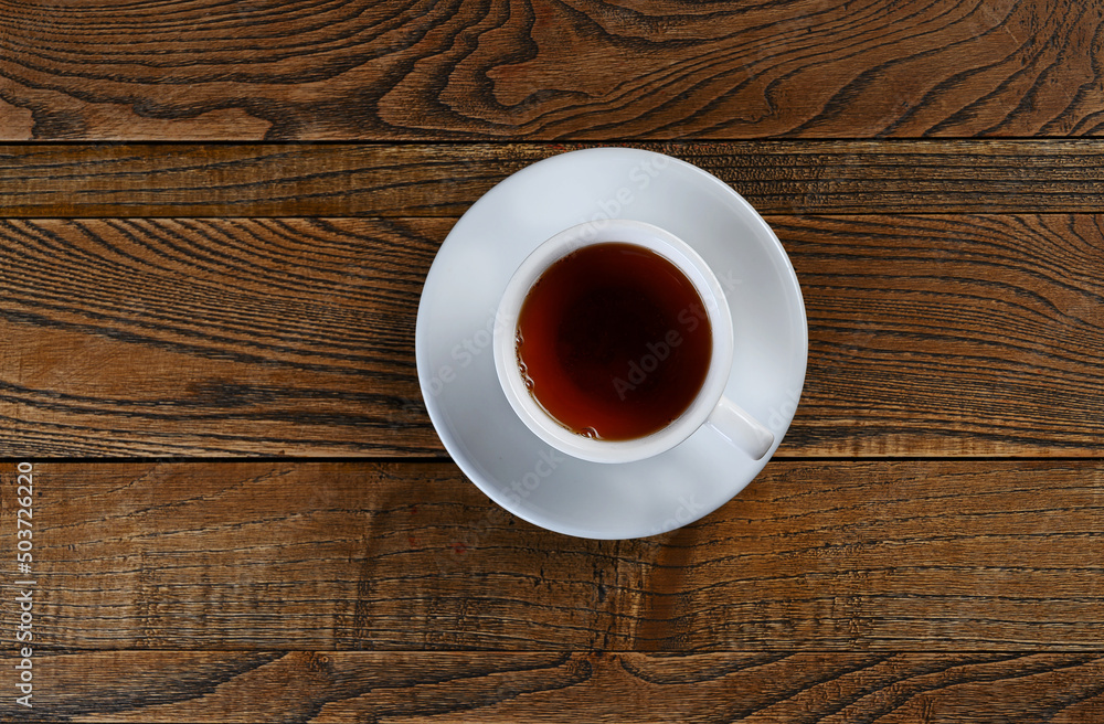 black tea poured in a white cup on a wooden background black tea poured in a white cup on a wooden background