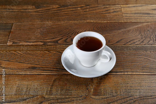 black tea poured in a white cup on a wooden background
