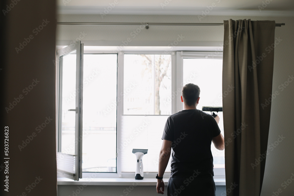 Man washing and cleaning window at home. Housework and housekeeping, home hygiene Man washing and cleaning window at home. Housework and housekeeping, home hygiene