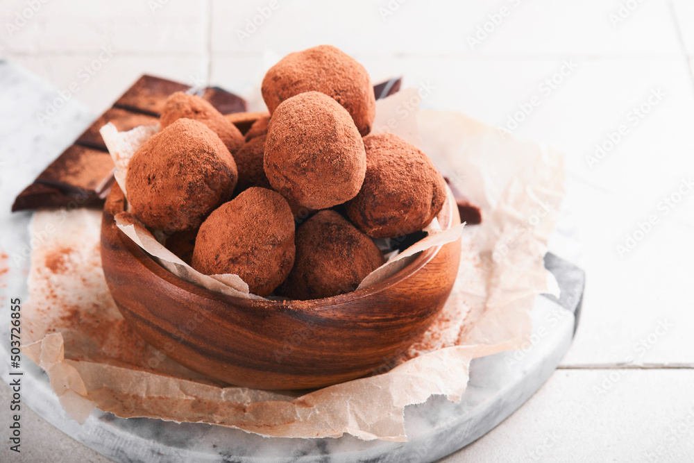 Chocolate truffles with cocoa powder in wooden dish on old cracked tile table background. Tasty sweet chocolate truffles candies. Valentine's Day and Mother's Day concept with copy space. Top view. Chocolate truffles with cocoa powder in wooden dish on old cracked tile table background. Tasty sweet chocolate truffles candies. Valentine's Day and Mother's Day concept with copy space. Top view.