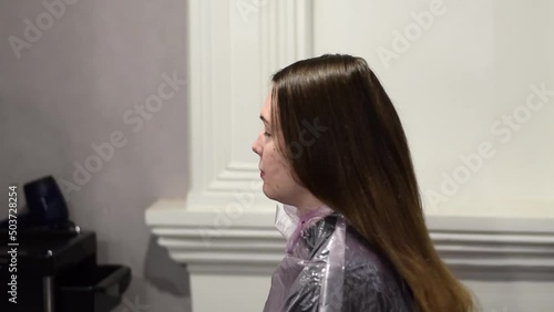 Hairdresser is loosening the hair of the young woman to examine their condition before starting to dye or style them in the beauty shop