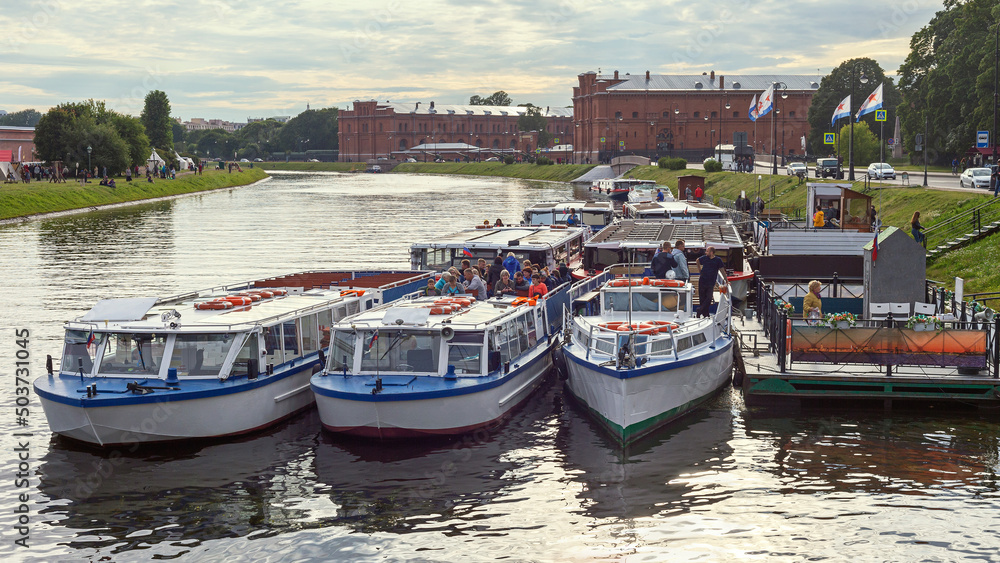 several small pleasure boats are parked on the Neva River in the center of the Russian city of St. Petersburg, waiting for tourists