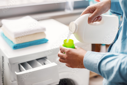 Photos A housewife carefully doses the detergent to put in the washing machine