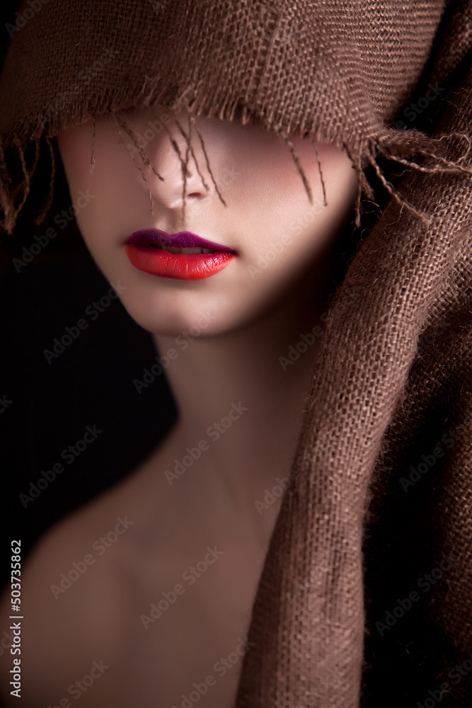 Close up of Young Beauty Fashion Model Face with Burlap Jute Fabric covering Eyes Red Lipstick. Perfect Skin Skincare Protection Concept. Close up of Young Beauty Fashion Model Face with Burlap Jute Fabric covering Eyes Red Lipstick. Perfect Skin Skincare Protection Concept.