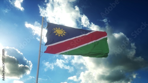 Flag of Namibia waving at wind against beautiful blue sky. 3d rendering © Dmitry