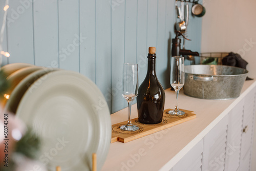 plates, glasses and a bottle of champagne or wine stand on a shelf in the kitchen against a gray wall