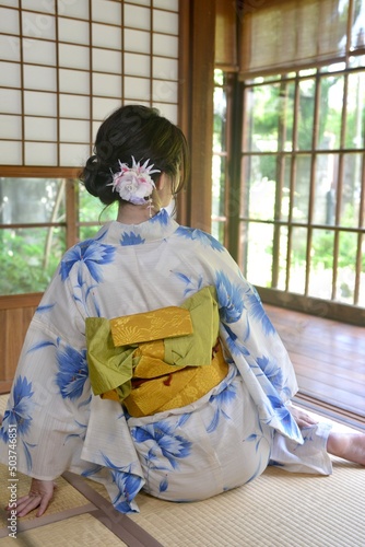 古民家の和室でくつろぐ浴衣を着た若い女性の後ろ姿	