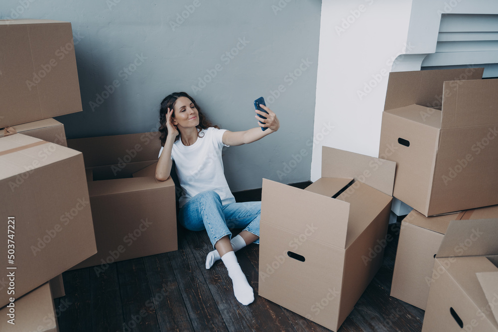 Happy woman unpacking boxes and taking selfie in new luxurious apartment. Success concept. Happy woman unpacking boxes and taking selfie in new luxurious apartment. Success concept.