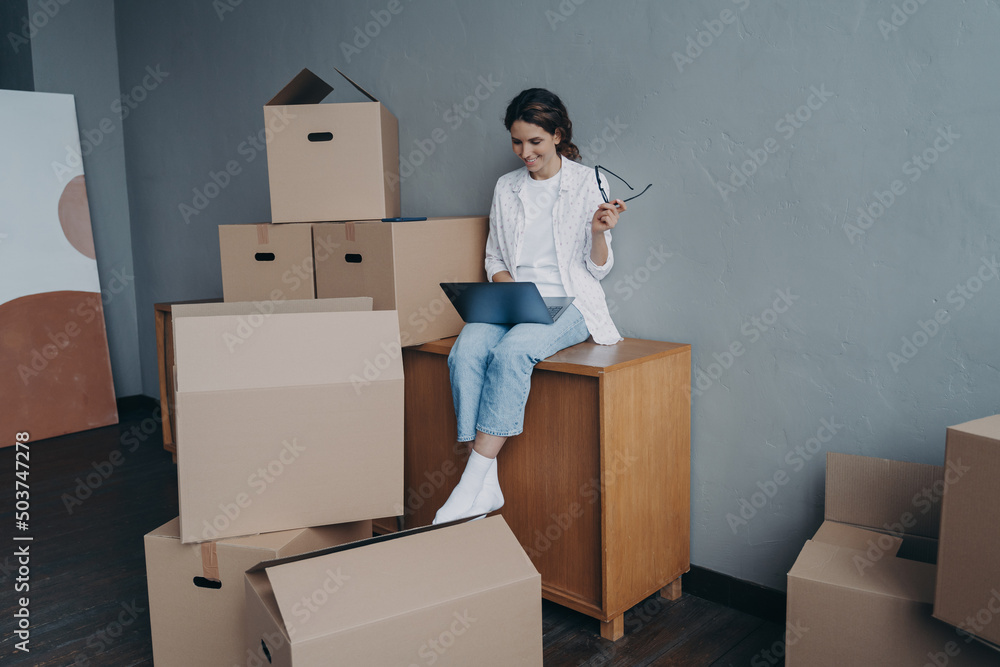 Businesswoman moves. Lady is sitting among cardboard containers and working on computer. Businesswoman moves. Lady is sitting among cardboard containers and working on computer.