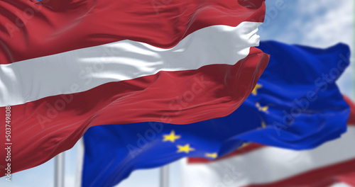 Detail of the national flag of Latvia waving in the wind with blurred european union flag in the background