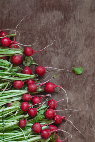 Fresh red radish with green leaves on a wooden rustic background.