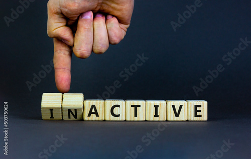 Active or inactive symbol. Businessman turns wooden cubes and changes the word Inactive to Active. Beautiful grey table grey background, copy space. Business and active or inactive concept.