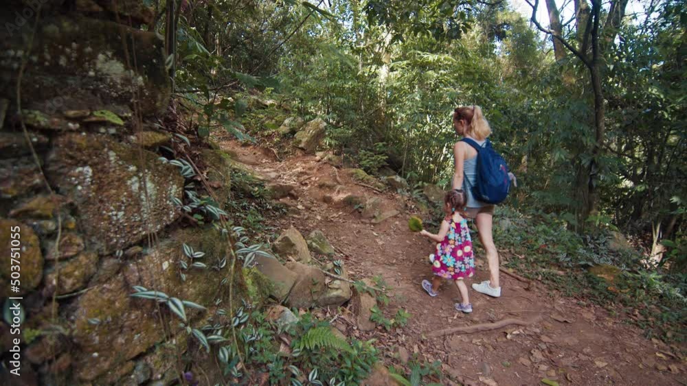 Family hike. Pregnant woman walks in the tropical forest with her kid Family hike. Pregnant woman walks in the tropical forest with her kid