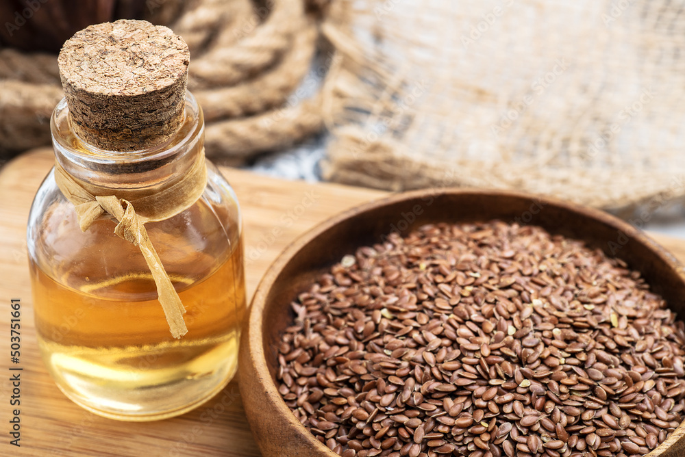 linseed oil in a glass bottle close-up and linseeds in a wooden bowl. Selective focus linseed oil in a glass bottle close-up and linseeds in a wooden bowl. Selective focus
