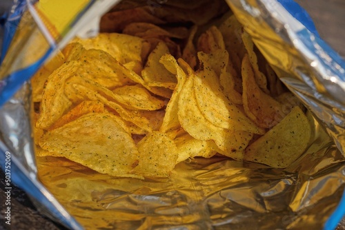 open plastic package with a bunch of dry yellow chips photo