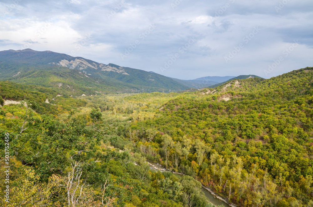 Picturesque view from the hill of the Ujarma fortress to the valley of the Iori river with dense oak forests climbing the mountain slope of the Caucasus Mountains in early autumn, Georgia Picturesque view from the hill of the Ujarma fortress to the valley of the Iori river with dense oak forests climbing the mountain slope of the Caucasus Mountains in early autumn, Georgia
