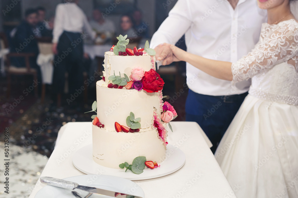The bride and groom cut a gorgeous wedding cake at a banquet.