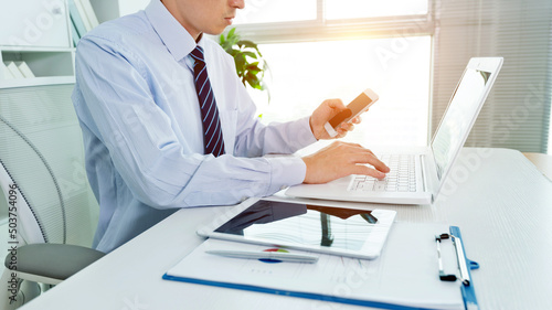Businessman in office using laptop, tablet and smart phone on the desk