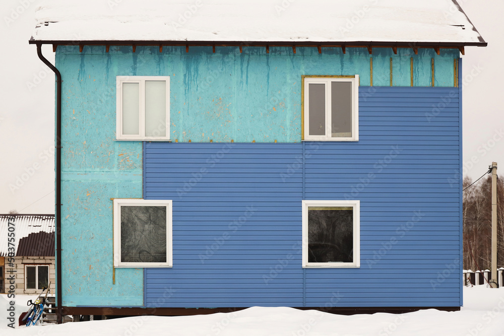 Wall covering of the old house with panels of vinyl siding. Construction and facade reconstruction. Repair of the house