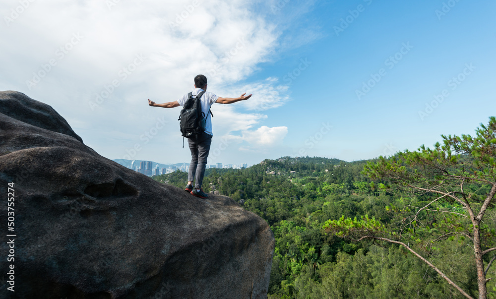 Cheering male hiker open arms at mountain peak