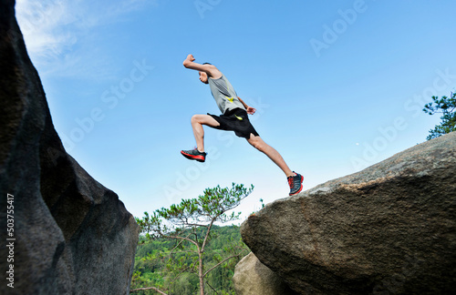 Young man jumping over the cliff