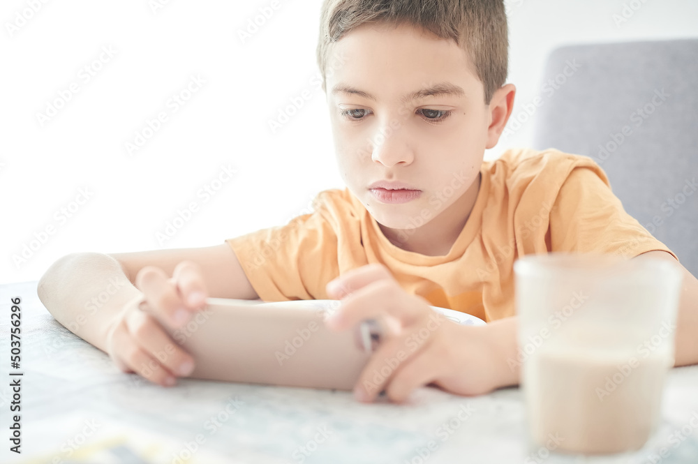 Primary school boy uses a mobile phone from early in the morning to play video games and watch videos on the internet. Problems of children addicted to screens. Primary school boy uses a mobile phone from early in the morning to play video games and watch videos on the internet. Problems of children addicted to screens.