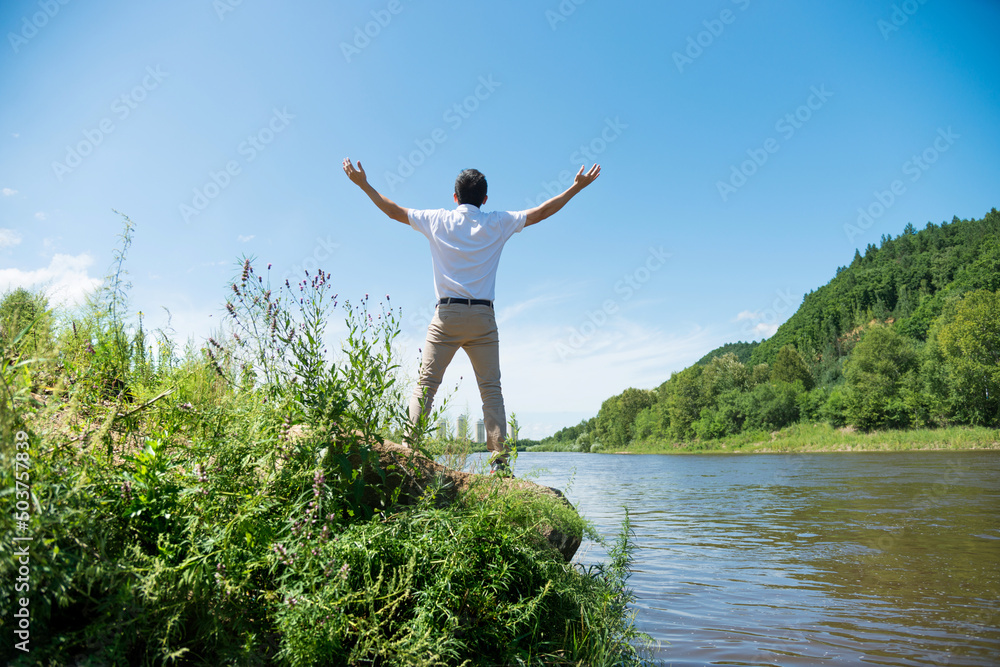 Happy young man with raised arms at lakeside Happy young man with raised arms at lakeside