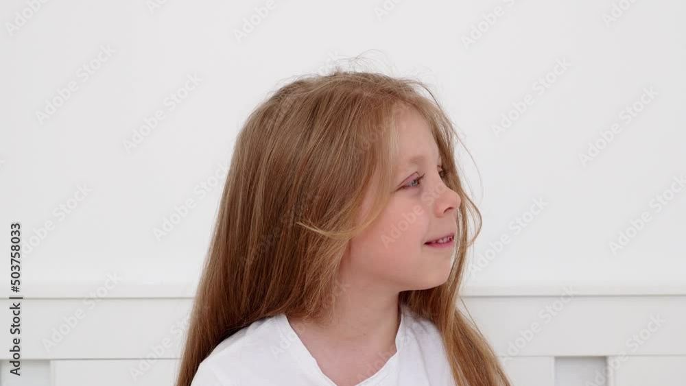 Portrait of a little girl in bed after sleeping. Portrait of a little girl with long blond hair and blue eyes. A child in pajamas smiles and laughs. Children's daily routine. Portrait of a little girl in bed after sleeping. Portrait of a little girl with long blond hair and blue eyes. A child in pajamas smiles and laughs. Children's daily routine.