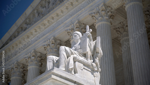 Closeup of sculpture on the Supreme Court building of Justice with Equal Justice slightly out of focus in the distance. photo