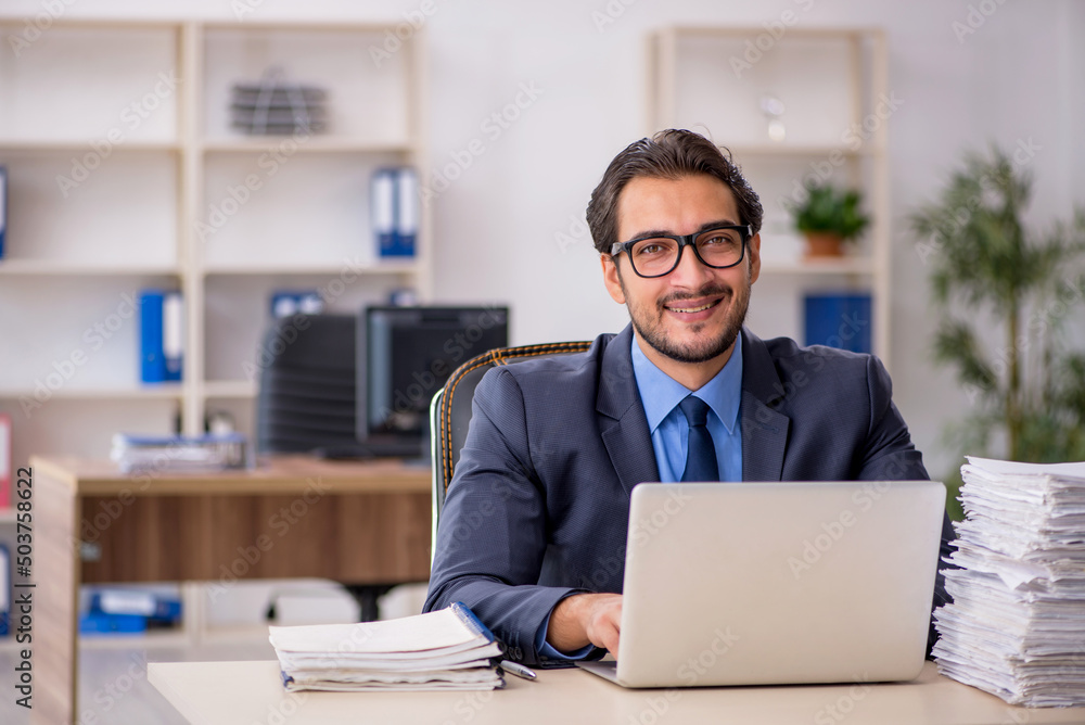 Young male employee and too much work in the office Young male employee and too much work in the office