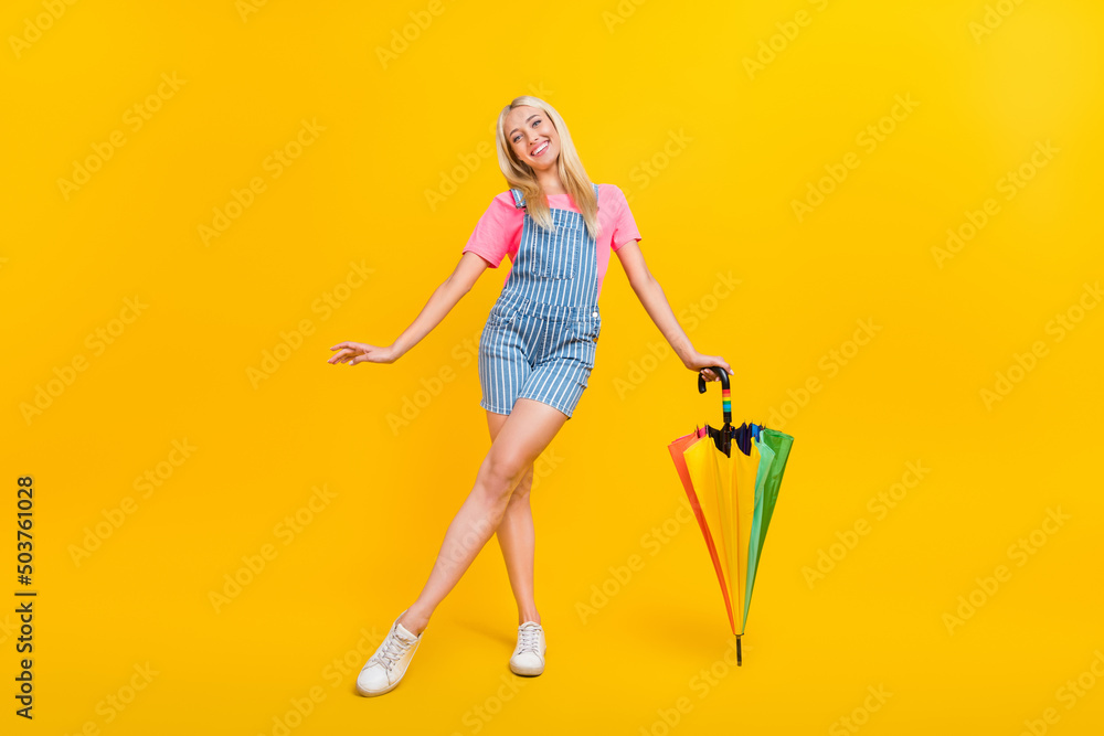 Fototapeta premium Full length portrait of satisfied peaceful lady hold umbrella toothy smile isolated on yellow color background