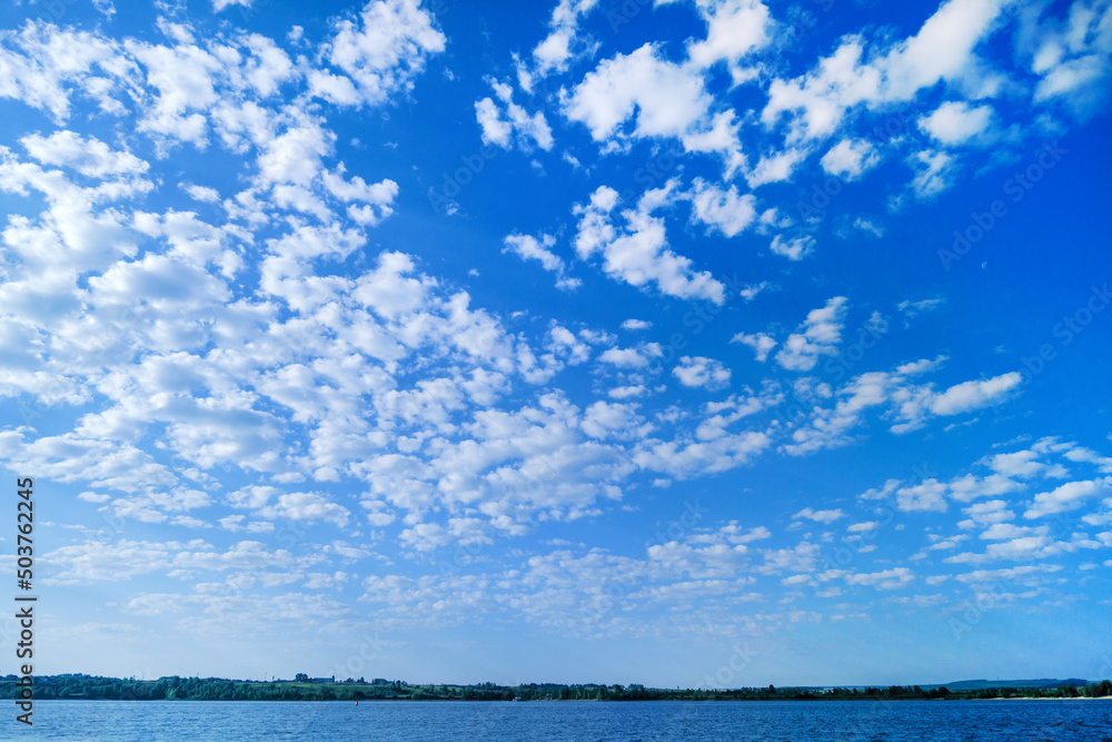 White clouds in the blue sky. Summer sky. Curly clouds on a sunny day. Heaven and infinity. Beautiful bright blue background. Light cloudy, good weather