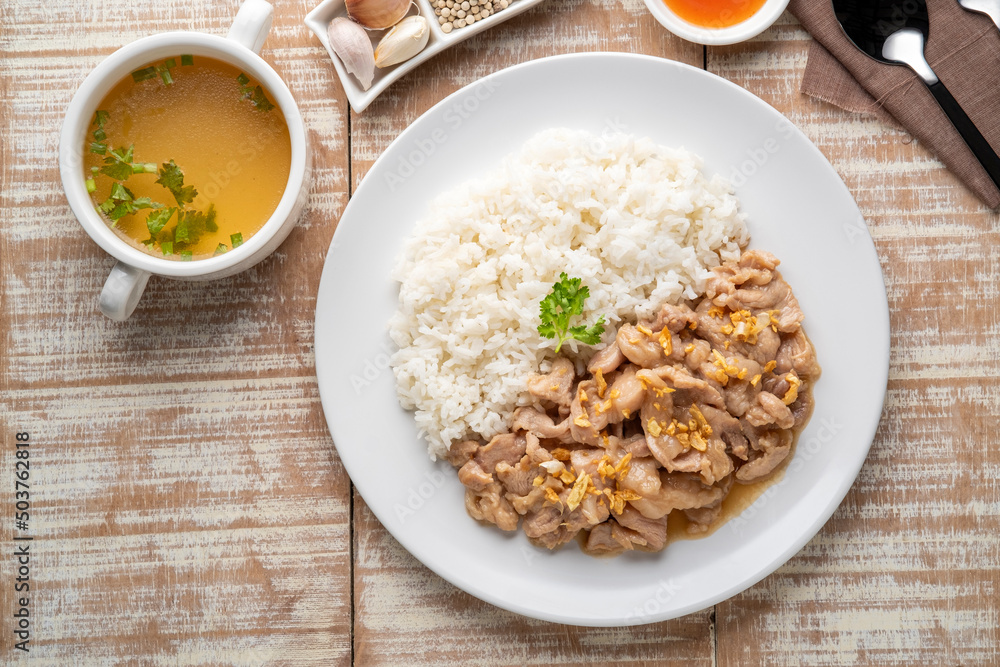 Stir-Fried Pork with Garlic and and pepper with cooked thai jasmine rice in white plate,popular Thai Street food.Top view Stir-Fried Pork with Garlic and and pepper with cooked thai jasmine rice in white plate,popular Thai Street food.Top view