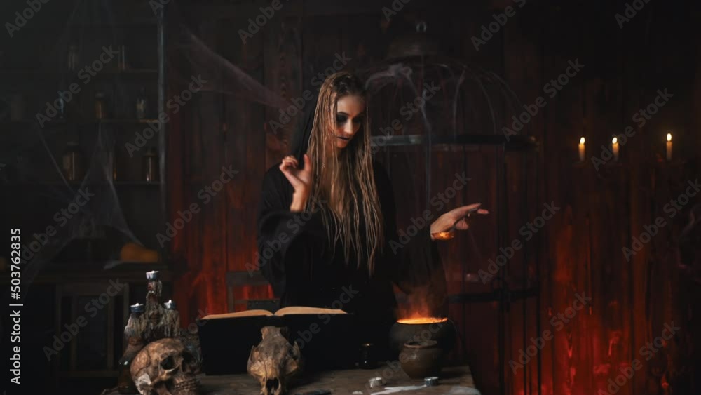 Halloween, witch use magic book and cauldron prepare poison or love potion. Black magic occult female wizard in dark room cage spider web human skull Necromancer cooking magic potion. voodoo. Handheld Halloween, witch use magic book and cauldron prepare poison or love potion. Black magic occult female wizard in dark room cage spider web human skull Necromancer cooking magic potion. voodoo. Handheld