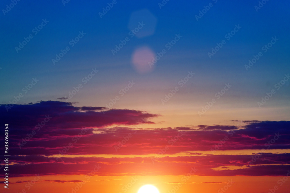 Meditative calmness and greatness. Red sun in the clouds. Great dramatic view. Amazing sky panorama. Clouds illuminated by the setting sun. Colorful sunset in the evening sky