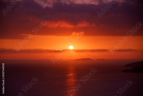 Colorful sunset in the evening sky. Red sun in the clouds. Amazing sky panorama. Clouds illuminated by the setting sun. Meditative calmness and greatness. Great dramatic view