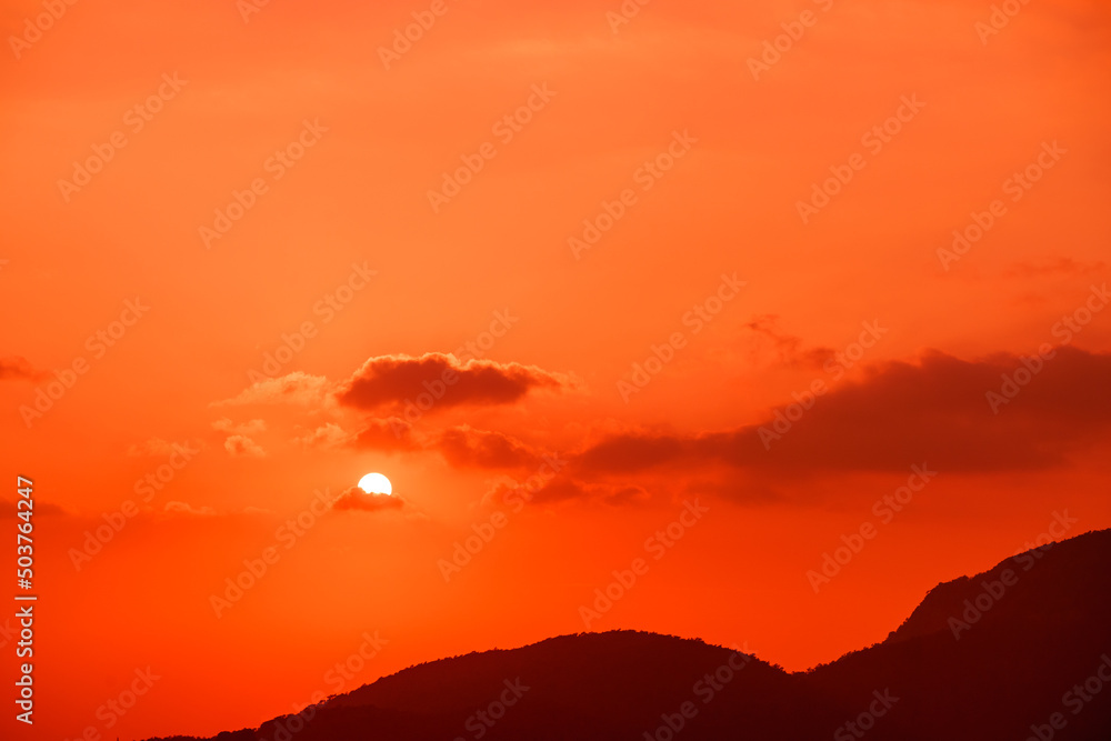 Fototapeta premium Great dramatic view. Amazing sky panorama. Meditative calmness and greatness. Red sun in the clouds. Colorful sunset in the evening sky. Clouds illuminated by the setting sun