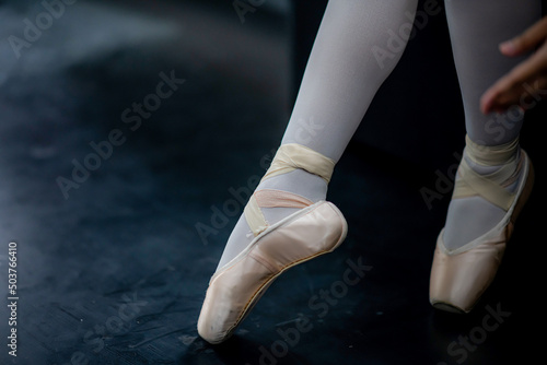 Professional female ballerina wears her ballet shoes to practice choreography.