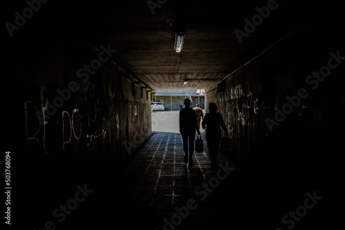 people walking in dark tunnel returning from shopping.