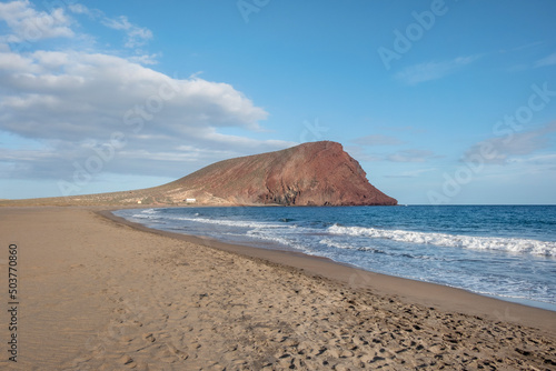 Solitary coastal landscape featuring a large empty beach known locally as Playa de la Tejita and the volcanic cone, Montana Roja, in the background, beautiful nature in Tenerife, Canary Islands, Spain photo