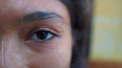Extreme close up of Indian Woman opening beautiful eye with blue iris. Attractive girl, a young female model looking at camera. Slow-motion, macro shot photo