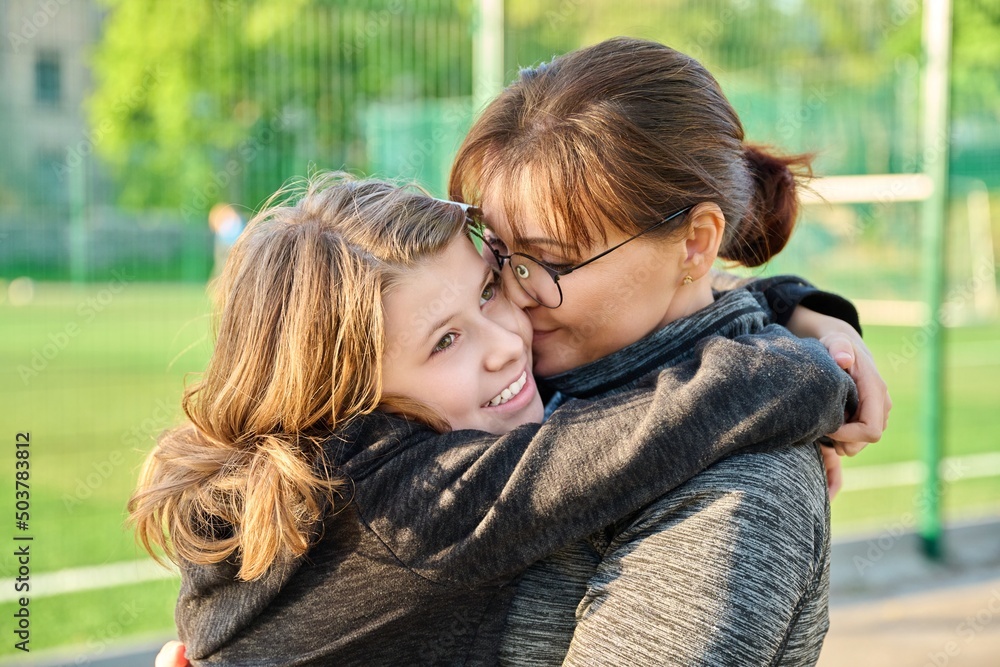 Portrait of happy mom and preteen daughter hugging together outdoor Portrait of happy mom and preteen daughter hugging together outdoor
