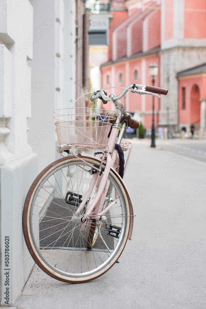 Vintage pink bycicle parked on the city street
