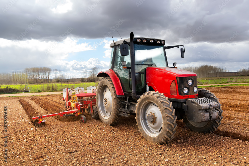 farmer on modern tractor with seed bins sowing the plowed field with farm equipment farmer on modern tractor with seed bins sowing the plowed field with farm equipment