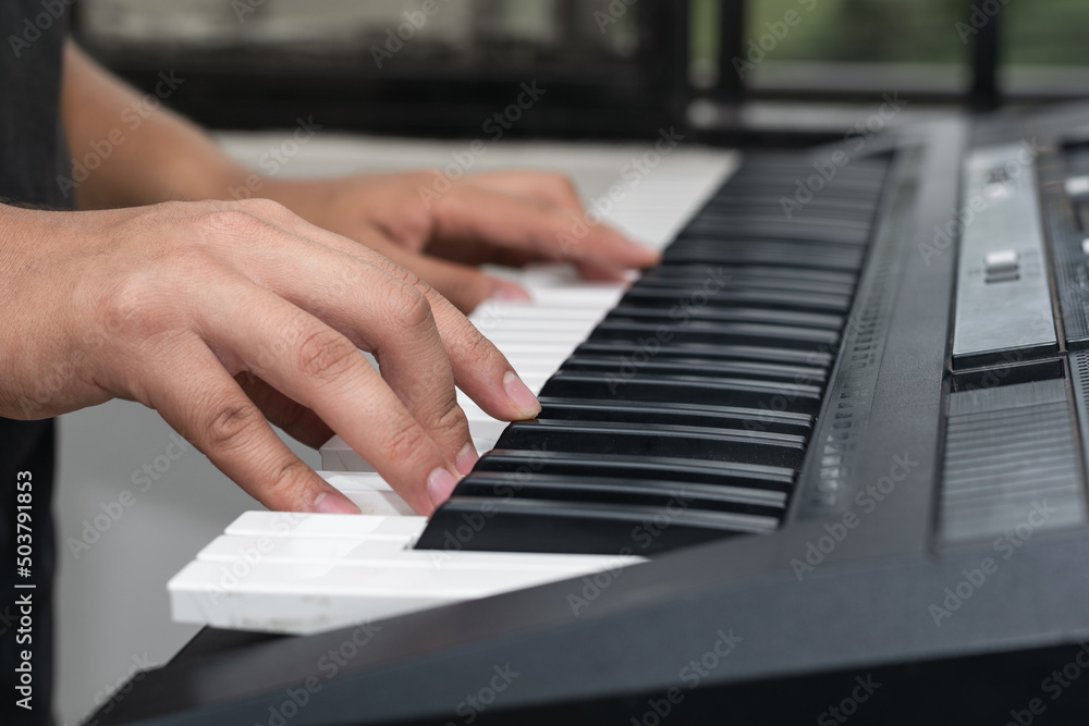 young latin man, playing musical piano notes on a synthesizer, boy practicing high notes. detail shot of man creating new music and rhythms. young latin man, playing musical piano notes on a synthesizer, boy practicing high notes. detail shot of man creating new music and rhythms.