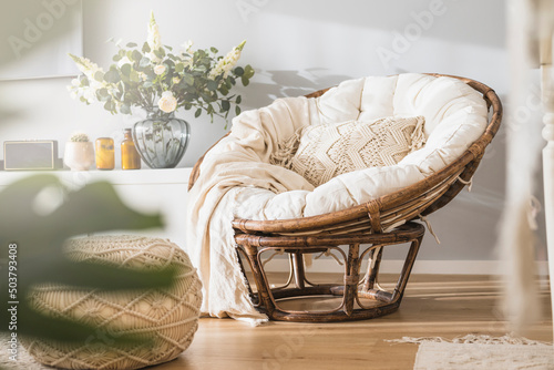 Rattan papasan chair with a beige pillow in a modern luminous apartment  photo