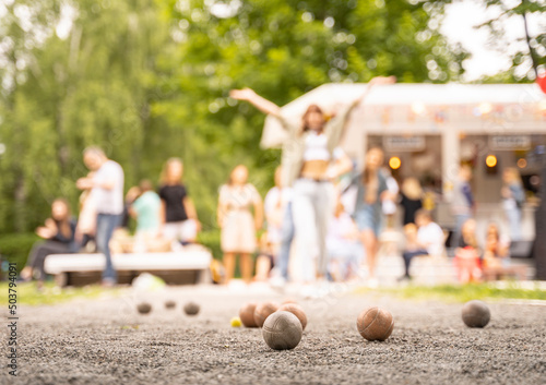 Friends playing petanque girl  celebrate victory above summer city cafe outdoor activity game