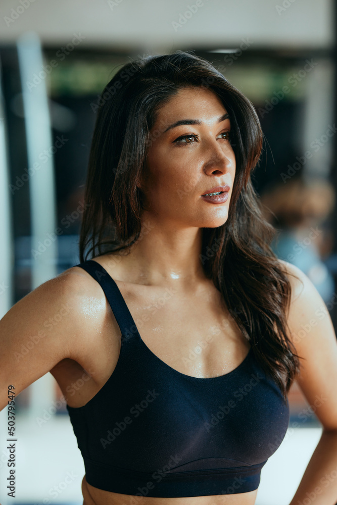 Portrait of a fit, muscular, sweaty sportswoman taking a break in a gym.