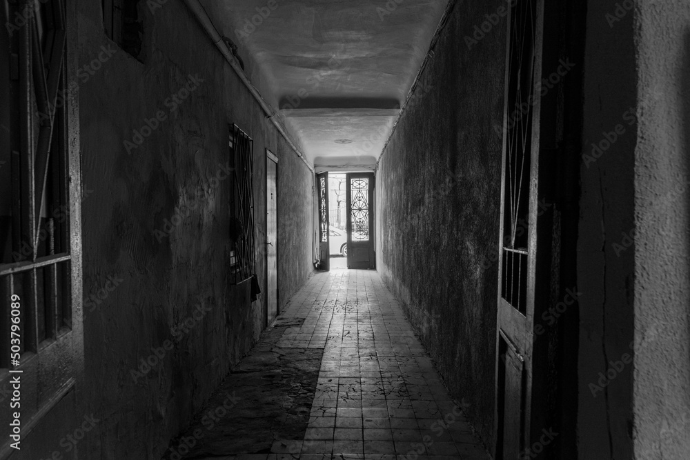 Photo inside the corridor of an old apartment building, the sun shines through the windows and front door Photo inside the corridor of an old apartment building, the sun shines through the windows and front door
