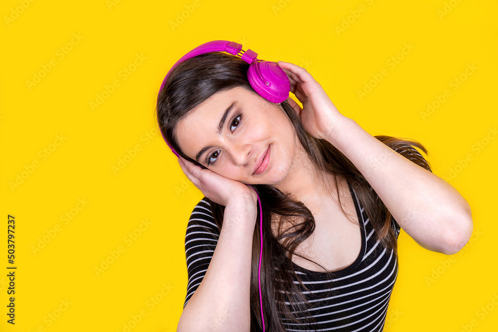 Portrait of beautiful smiling girl with long hair. The young woman wears jeans and a striped t-shirt and uses headphones to listen to music. Portrait of beautiful smiling girl with long hair. The young woman wears jeans and a striped t-shirt and uses headphones to listen to music.